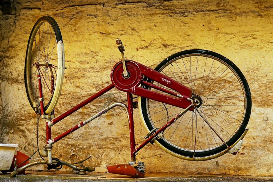 A vintage red bicycle frame against a textured wall.